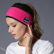 Woman wearing pink sports headband with Bluetooth controls for wireless music during workouts and activities