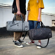 Two people holding gray and black waterproof gym bags with adjustable straps, suitable for travel and sports gear.