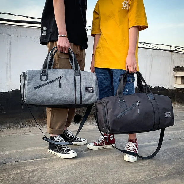 Two people holding gray and black waterproof gym bags with adjustable straps, suitable for travel and sports gear.